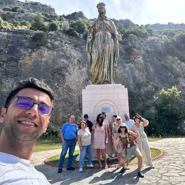 A tour group by a statue of the Virgin Mary